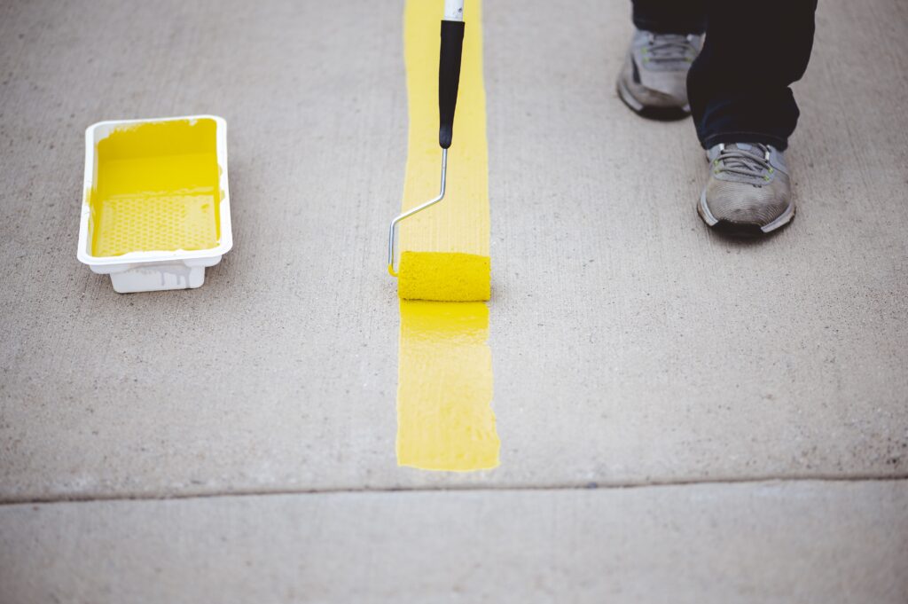 view person repainting parking lines asphalt parking lot with yellow paint